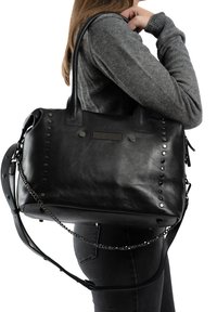 Zwarte lederen handtas met bovenhandvaten en een afneembare schouderband. Voorzien van metalen studs en een kettingaccent op de band. Gladde textuur.