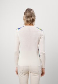 Rippstrick-Pullover in Cremefarbe mit bunten Musterakzenten auf den Schultern. Lange Ärmel und taillierte Passform. Weicher Stoff.
