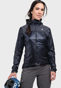 Schwarze leichte Jacke mit Reißverschluss, kontrastierenden grauen Schultern und elastischen Manschetten, getragen mit grauen Hosen und einem blauen Helm.