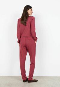 Bordowy zestaw do noszenia w domu z długimi rękawami i zwężanymi spodniami, charakteryzujący się luźnym krojem i elastycznym pasem, uzupełniony bocznymi kieszeniami.