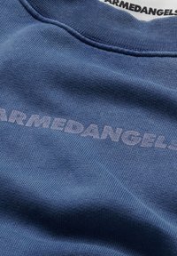 Sudadera de algodón azul con textura acanalada, con "ARMEDANGELS" en una impresión blanca y en negrita en la parte frontal. Diseño de cuello redondo.