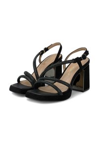 Sandalias de tacón bloque abiertas de dedo en negro, con tacones gruesos y brillantes, tiras cruzadas que brillan y cierres de hebilla en el tobillo sobre plantillas beige.