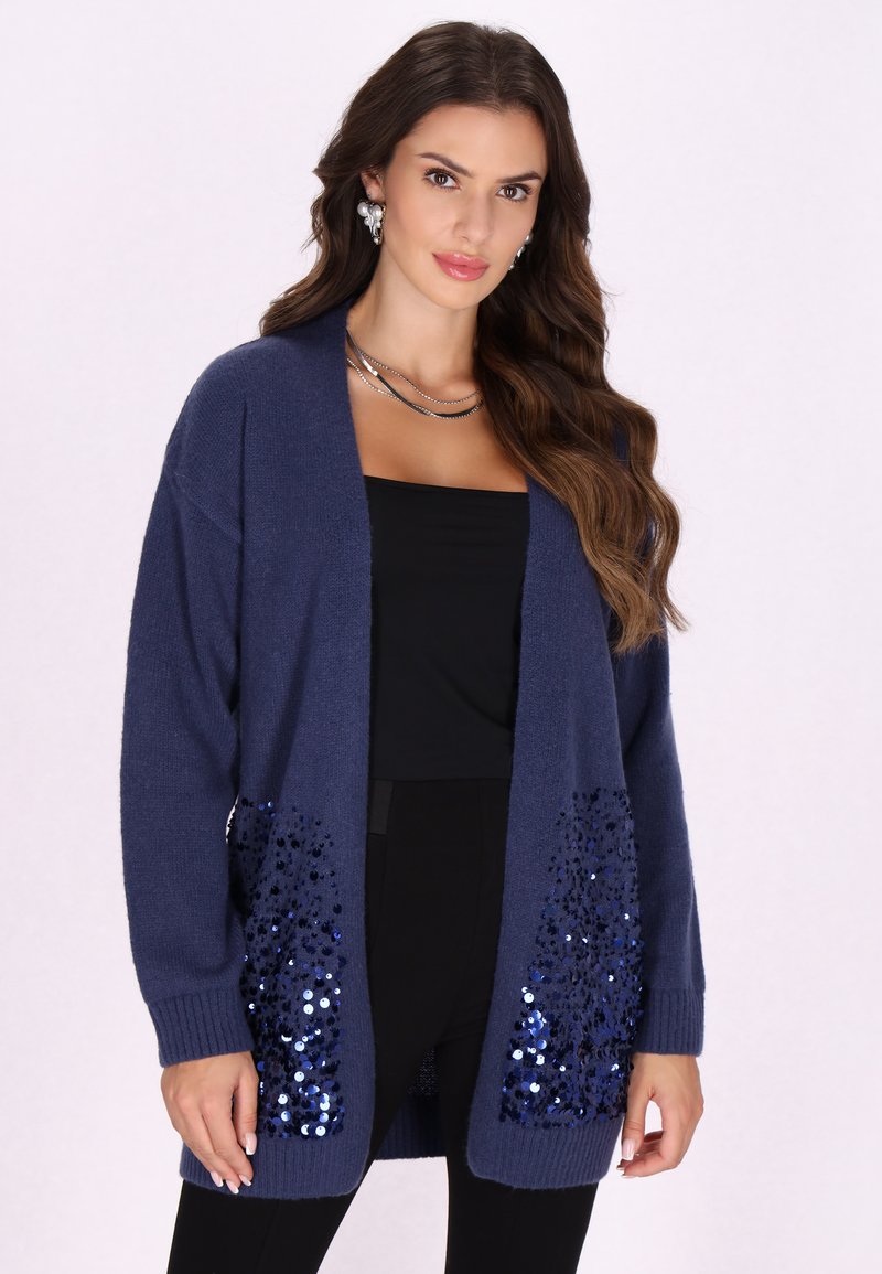 Cardigan navy realizzato in morbido tessuto a maglia, con apertura frontale e tasche decorate con paillettes blu. Le maniche a costine e l'orlo migliorano la trama.