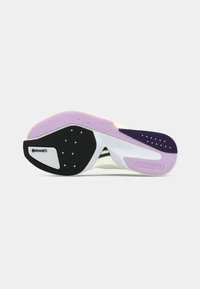 Suela de zapato deportivo en blanco y negro con un degradado púrpura y amarillo; goma texturizada con indentaciones circulares y etiqueta "ADIZERO".