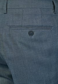 Dunkelblauer Stoff mit strukturierter Webart, ausgestattet mit einer Gesäßtasche, einem einzelnen schwarzen Knopf und maßgeschneiderten Nähdetails.