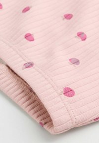 Nahaufnahme eines rosa gerippten Stoffes mit kleinen, verstreuten dunkelrosa und lila Herzmustern und sichtbaren Nähten an der gefalteten Kante.