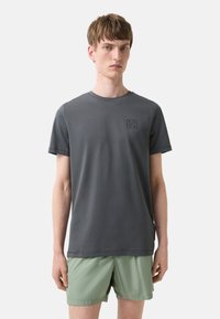Mørkegrå kortærmet T-shirt lavet af bomuld, med et lille sort geometrisk logo på brystet. Regular fit, rund hals.