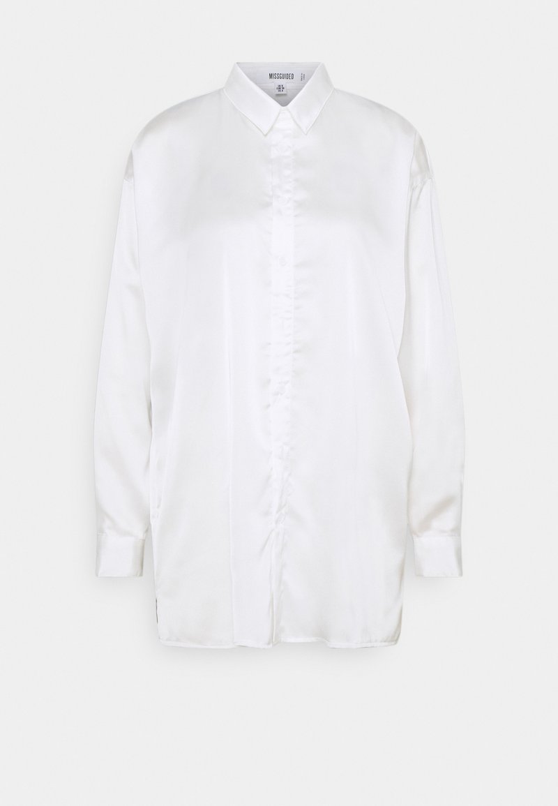 Chemise blanche en satin à manches longues avec ouverture boutonnée et col pointu, présentée sur un fond gris clair.