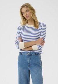 Blue and cream striped sweater with a round neck and ribbed cuffs, paired with high-waisted light blue jeans. Smooth knit texture.