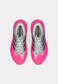 Ζευγάρι ροζ και γκρι παπούτσια για τρέξιμο με λευκά κορδόνια και μαύρες ρίγες, από πάνω σε λευκό φόντο.