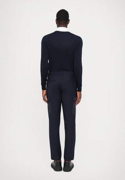 Combinația de pulover bleumarin și pantaloni cargo. Puloverul are guler rotund, mâneci lungi; pantalonii dispun de buzunare laterale și un finisaj de țesătură neted.