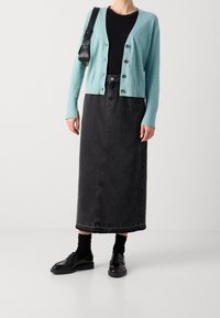 Light blue cardigan with buttons, black long denim skirt, black shoes with thick soles, and black socks. Simple and clean design.