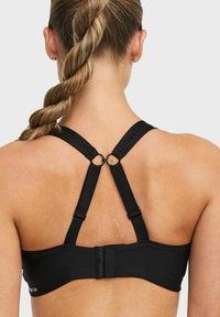 Svart sportbh med justerbara remmar, hakeknäppning på baksidan och ett slätt, texturerat tyg för komfort och stöd.