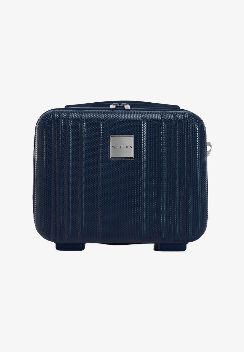 Marineblauwe harde koffers met een textuur, verticale ribbels, metalen logo-plaat en een rits aan de bovenkant. Compact rechthoekige vorm met vier voeten.