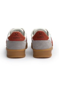 Weiße und graue Wildledersneaker mit orangefarbenen Akzenten, mit einem Logo an der Ferse, einer strukturierten Rückseite und einer Gummisohle.