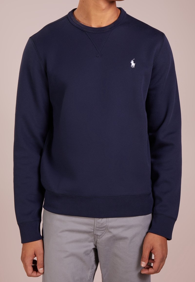 Navy crewneck-tröja i mjuk bomullsblandning, med ribbade muddar och nederkant, samt en vit logotyp på vänster bröst.