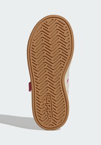 Podešev sandálu Adidas s vzorem šipek, vybavená lehkou hnědou gumovou základnou a texturovaná hlubokými drážkami pro lepší trakci.