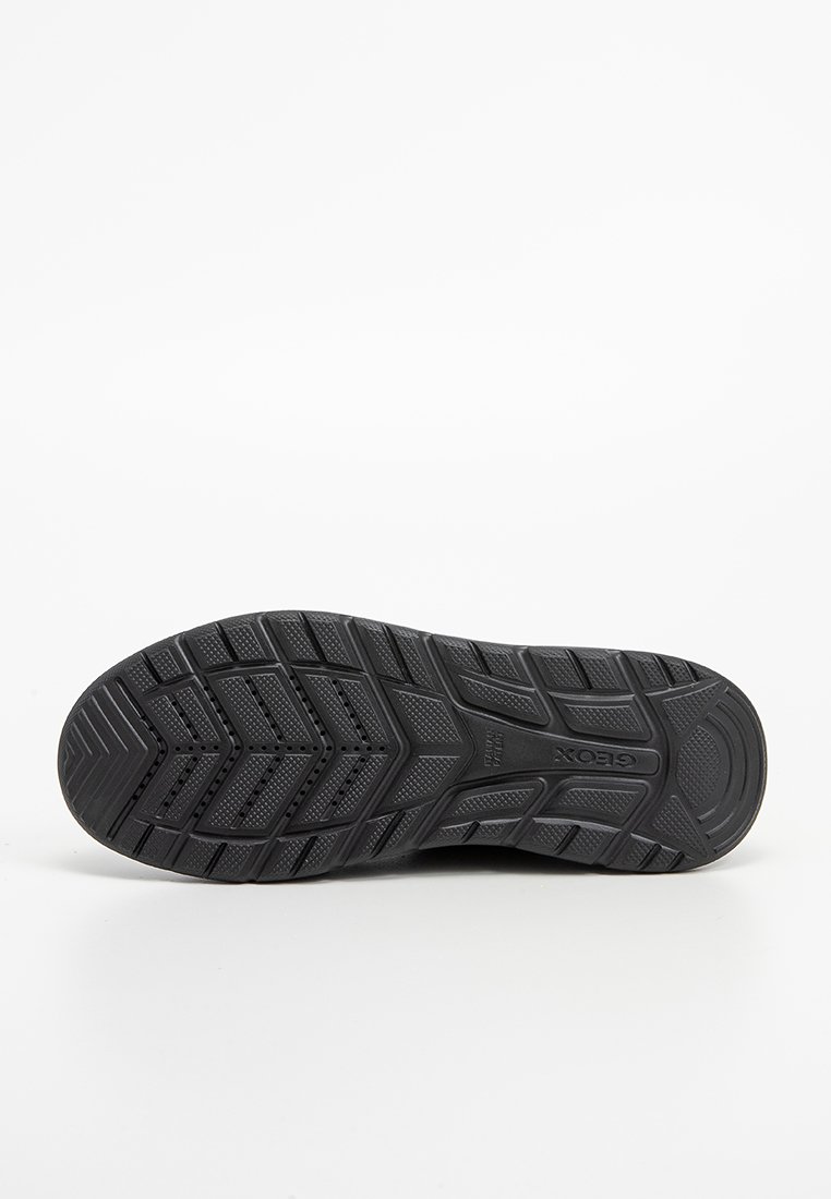 Sole di una scarpa Geox nera con suola a disegno e fori di ventilazione, mostrata piatta su uno sfondo bianco.