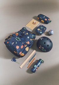 Un sac à dos bleu marine avec des motifs de planètes colorées, accompagné d'un casque, d'une boîte à lunch, de fournitures scolaires, d'une règle et d'une bouteille d'eau, le tout sur une surface grise.
