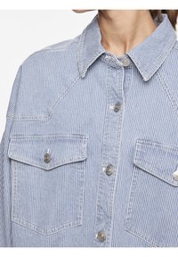 Blå och vit randig skjorta med krage, två framfickor, silverknappar och kontraststickning.