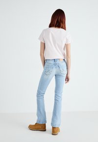 Light pink striped t-shirt with short sleeves, paired with light blue flared jeans and tan ankle boots. Simple design and casual fit.