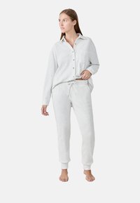 Lichtgrijze geribbelde loungewear set met een knoopsluiting lange mouw shirt met een zak en joggingsbroek met strikkoord en geborduurde enkels.