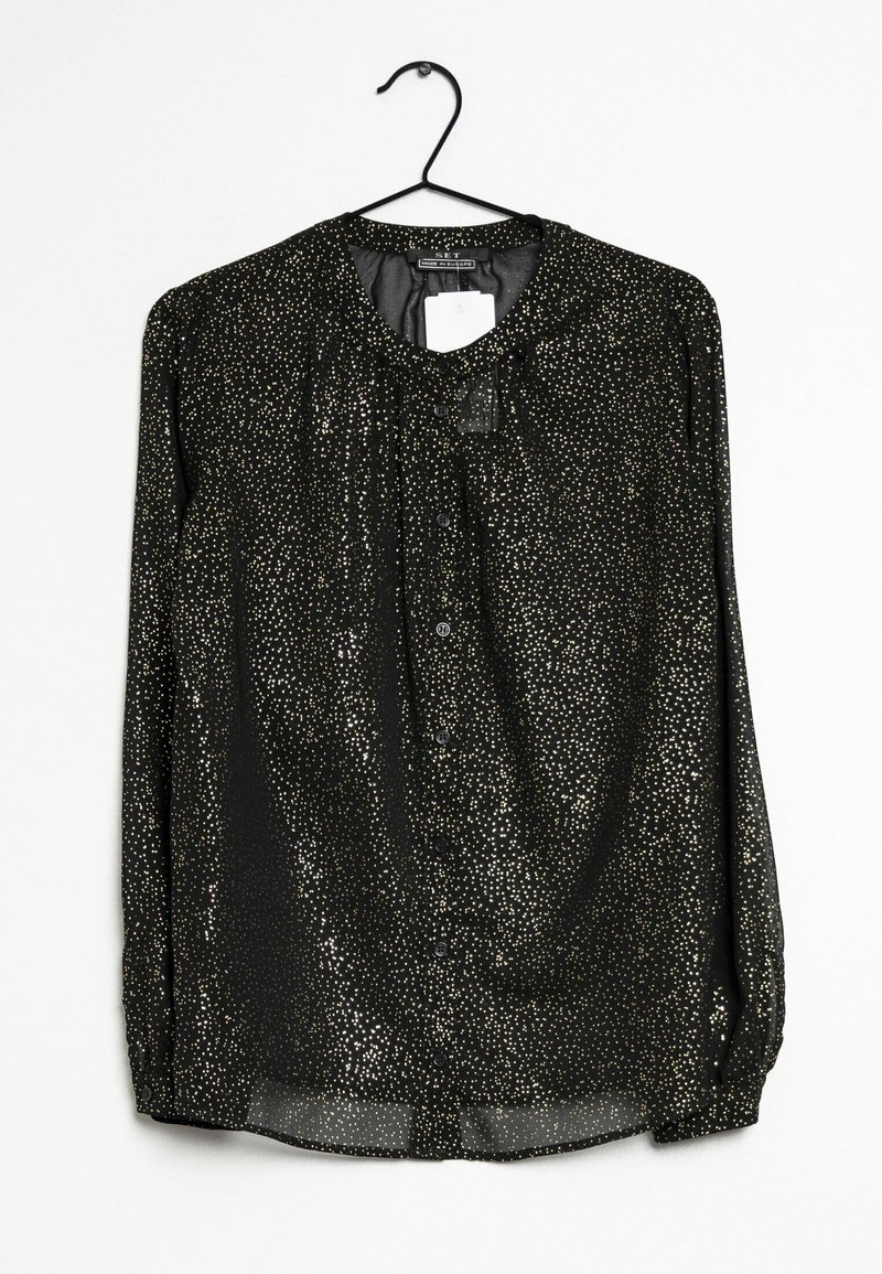Musta blusa, jossa on pyöreä pääntie ja pitkät hihat, koristeltu kultaisilla pilkuilla, napit edessä ja läpikuultavaa materiaalia.