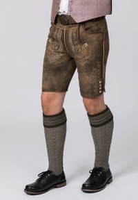 Brown leather shorts with ornate embroidery, paired with textured gray knee-length socks and black shoes. A silver belt buckle completes the look.