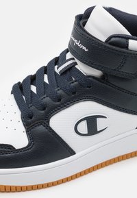 Wysokie tenisówki z granatowo-białej skóry, z perforowanymi detalami, sznurowanym zapięciem i gumową podeszwą w kolorze gumy z akcentem logo.