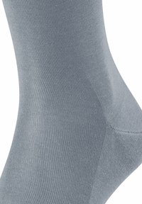 Calzino grigio realizzato in un materiale liscio ed elastico, con texture a coste e una vestibilità aderente attorno alla caviglia.