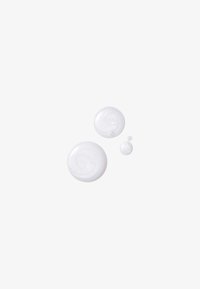Tre gocce circolari di crema bianca traslucida, di dimensioni diverse, con una superficie liscia e sottili motivi vorticosi.