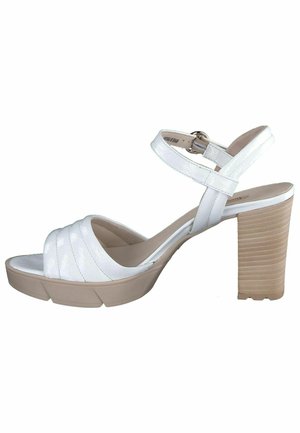 Witte hakken sandalen met een brede, gestructureerde band over de teen, een verstelbare enkelband, en een chunky, beige ribbelige hak.