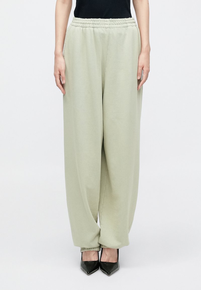 Jasnozielone dresy z elastycznym pasem i zwężanymi ściągaczami, wykonane z miękkiego materiału, w połączeniu z czarnymi butami na szpic.