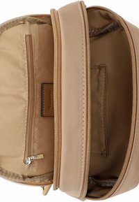 Pruunist nahast koti sisu mitme sektsiooniga, sealhulgas lukuga tasku, tekstuurse voodri ja küljele kinnitatud brändisildi.