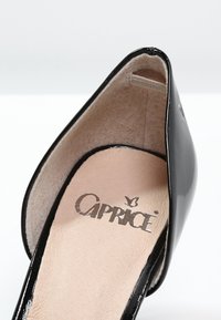 Escarpin en cuir verni noir à talon haut avec un embout pointu et une semelle intérieure beige portant le logo "Caprice" en impression métallique. Texture lisse.