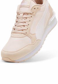Scarpa sportiva rosa chiaro con tomaia liscia, dettagli bianchi e suola imbottita. Lacci e logo Puma visibili sulla linguetta.