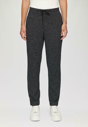Grijze, gestructureerde joggers met een tailleband met trekkoord, taps toelopende benen en zijzakken, gecombineerd met witte sneakers op een neutrale achtergrond.