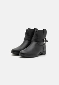 Bottines en cuir noir avec un petit talon, bout rond, sangle réglable avec détail de boucle, et texture lisse.