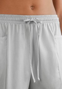 Lichtgrijze, zachte stoffen shorts met een elastische tailleband en een gestrikt trekkoord, voorzien van zijzakken en een gladde textuur.
