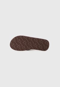 Talpa de pantof din cauciuc maro cu un model geometric texturat. Talpa are o formă rotunjită și o margine netedă. Material ușor și flexibil.