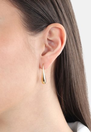 Orecchini a goccia in oro con una finitura lucida. Il design presenta una forma slanciata ed allungata che si restringe a punta.