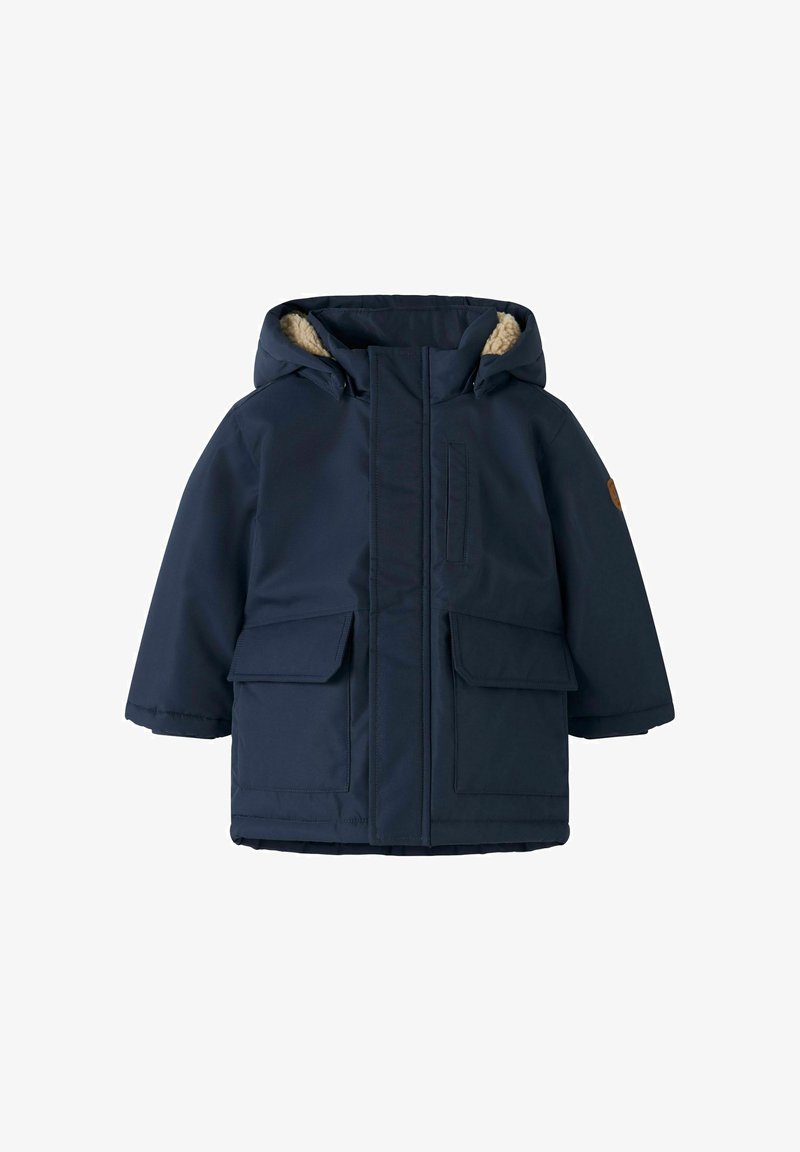 Mornarsko plava parka jakna s kapuljačom obloženom umjetnim krznom, prednjim zatvaranjem na zip i dva velika džepa s preklopom. Ima mali logotip na rukavu.