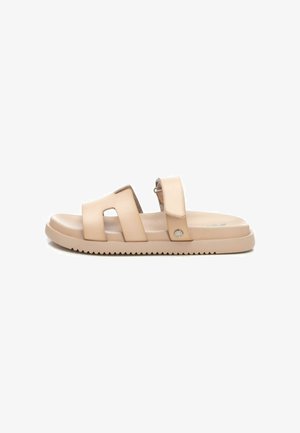 Sandalias beiges con correas dobles, diseño de corte, plantilla texturizada y suela estriada. Presenta un pequeño acento metálico en el costado.