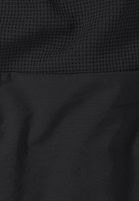 Zwarte sportstof met een gestructureerd bovenste gedeelte met een rasterpatroon en een glad onderste gedeelte, wat een contrasterend ontwerp creëert in een monochroom palet.