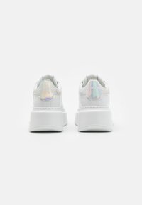 Bijele platforme tenisice s sjajnim, iridescentnim detaljem na peti, koje na stražnjem dijelu imaju "KARL LAGERFELD" branding i teksturiranu potplat.