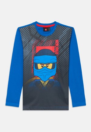 Plava košulja dugih rukava s crnim prednjim panelom na kojem je LEGO ninja lik u plavoj maski i žutim naočalama, okružen crvenim i plavim linijama.