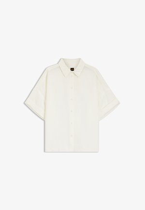Camisa blanca de manga corta con botones y cuello, de corte holgado y con costuras laterales sutiles sobre un fondo blanco.
