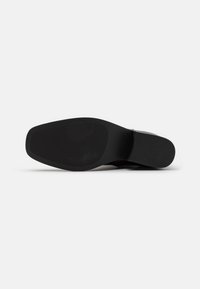 Suela de zapato negra con una superficie lisa y plana. Hecha de goma, presenta una forma redondeada y un ligero tacón. Sin patrones ni marcas visibles.