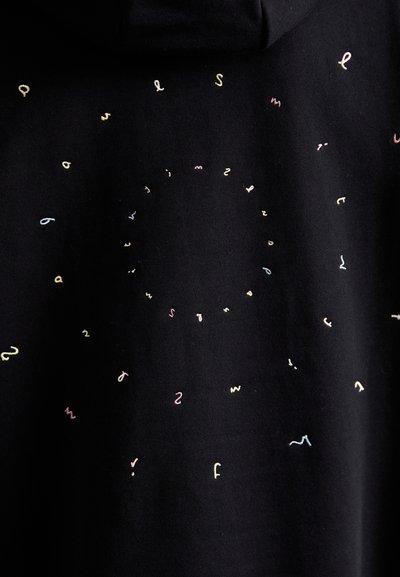 Sort hættetrøje med spredt, flerfarvet, krøllet broderi i forskellige pastelfarver, der danner et cirkelt mønster. Blød bomuldsstruktur.