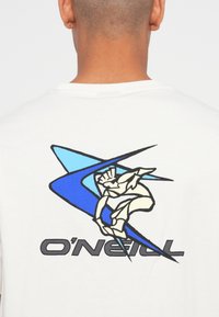 Pogled s leđa osobe koja nosi bijelu majicu s plavim apstraktnim valom i grafikom surfanja, a na leđima se nalazi natpis "O'Neill".